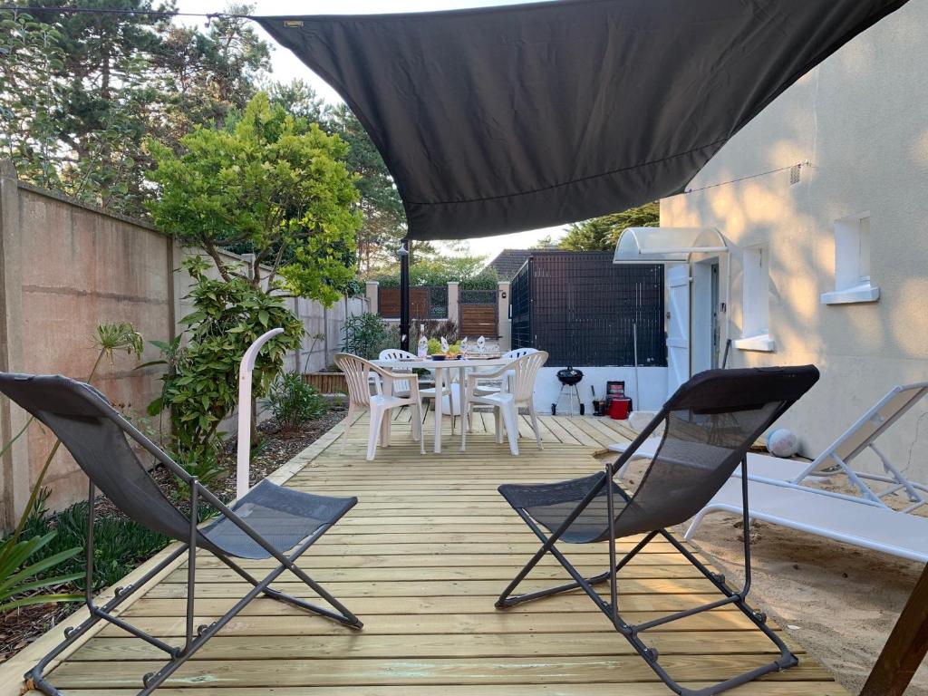 un patio avec une table, des chaises et un parasol dans l'établissement La mélodie des Vagues, à Portbail