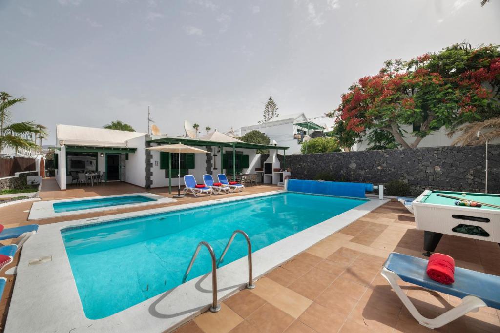 a swimming pool with chairs and a house at Villa Mirafondo in Tías