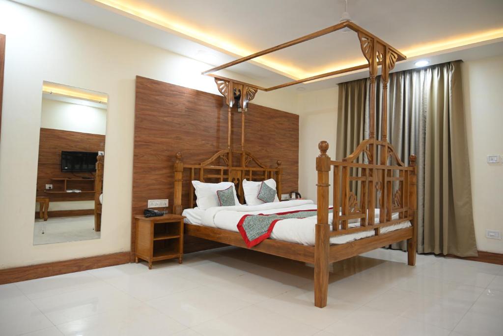 奥拉奇哈Orchha Club and Resort - OCR的一间卧室配有一张带镜子的木制天蓬床