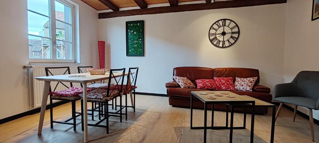 een woonkamer met een bank, een tafel en stoelen bij La Grenouille - Centre Ville - Proche Parking Gratuit - Commerces à Proximité in Sélestat