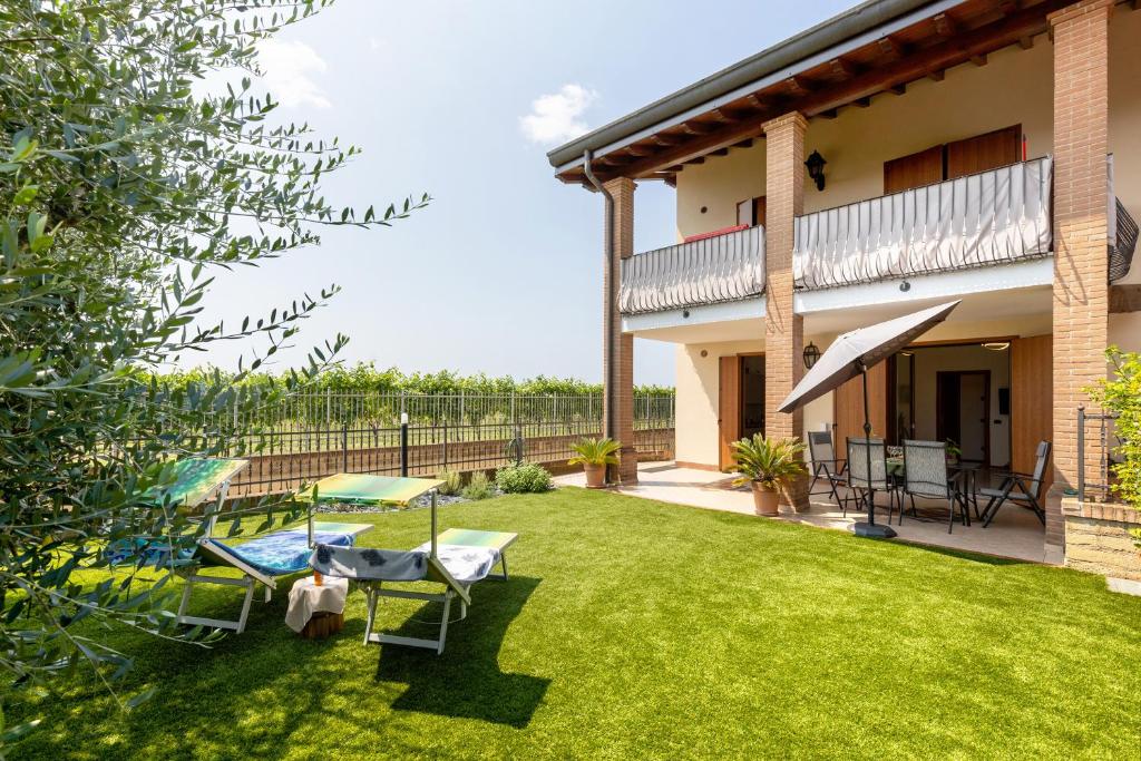 une cour avec des chaises longues et une maison dans l'établissement Katy Lake Lavanda, à Peschiera del Garda
