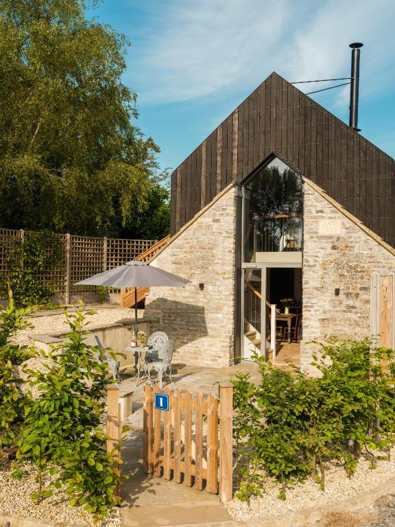 a barn conversion with a table and an umbrella at The Old Winery Cottage No1 in Shepton Mallet
