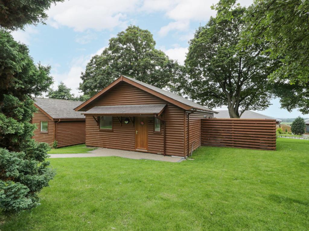 a wooden cabin with a grassy yard in front of it at Luxury Lodge 69 in Rhyl