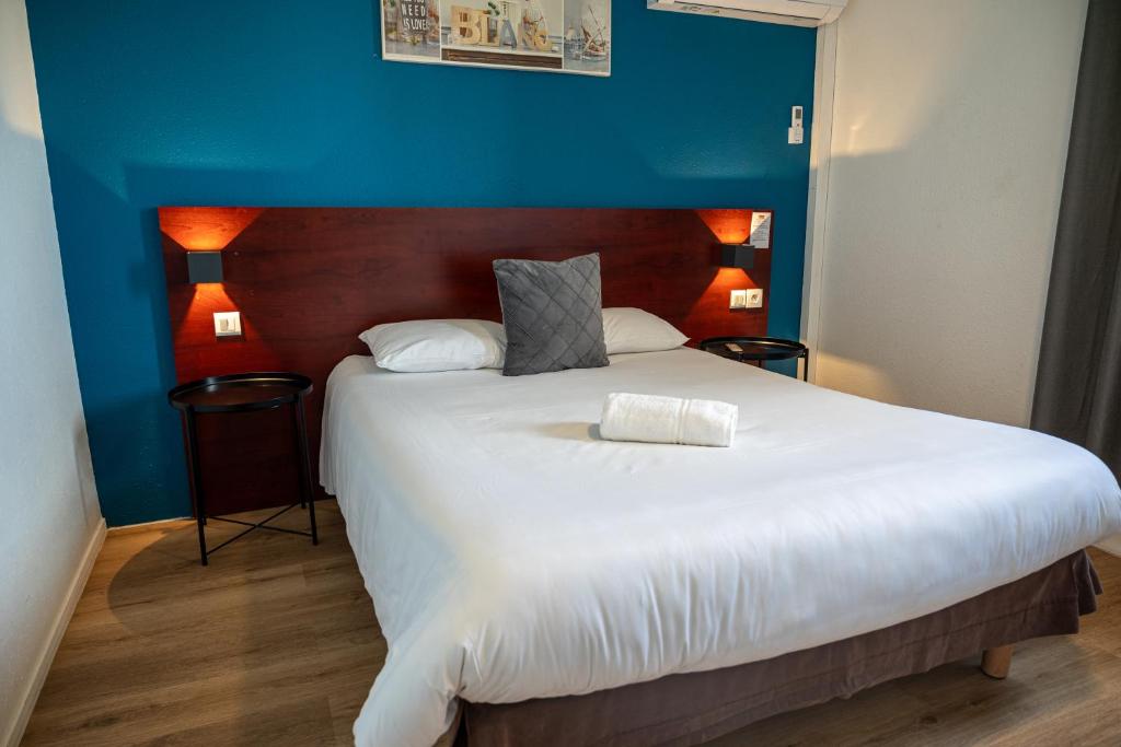 Un dormitorio con una gran cama blanca con una pared azul. en Initial by Balladins Lyon Villefranche-sur-Saône, en Villefranche-sur-Saône