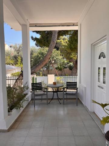Un patio con una mesa y sillas en un porche. en Panos Apartments, en Artemida