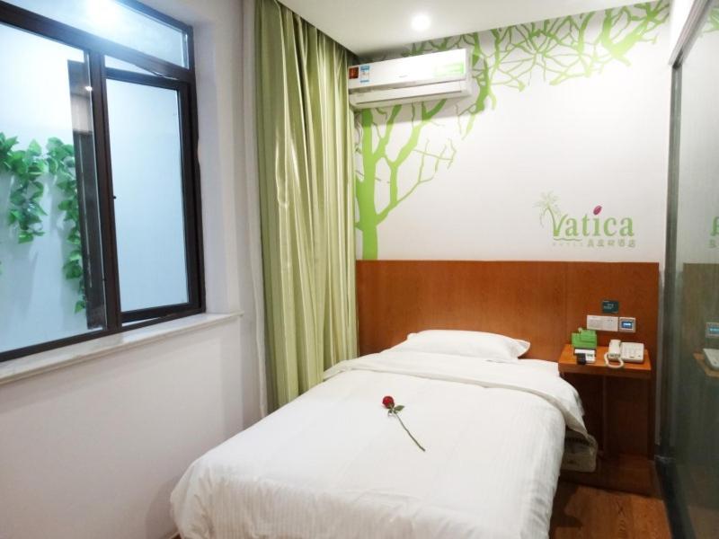 a bedroom with a white bed and a window at Vatica Jiangsu Suzhou Changshu Shimao Residence Hotel in Changshu