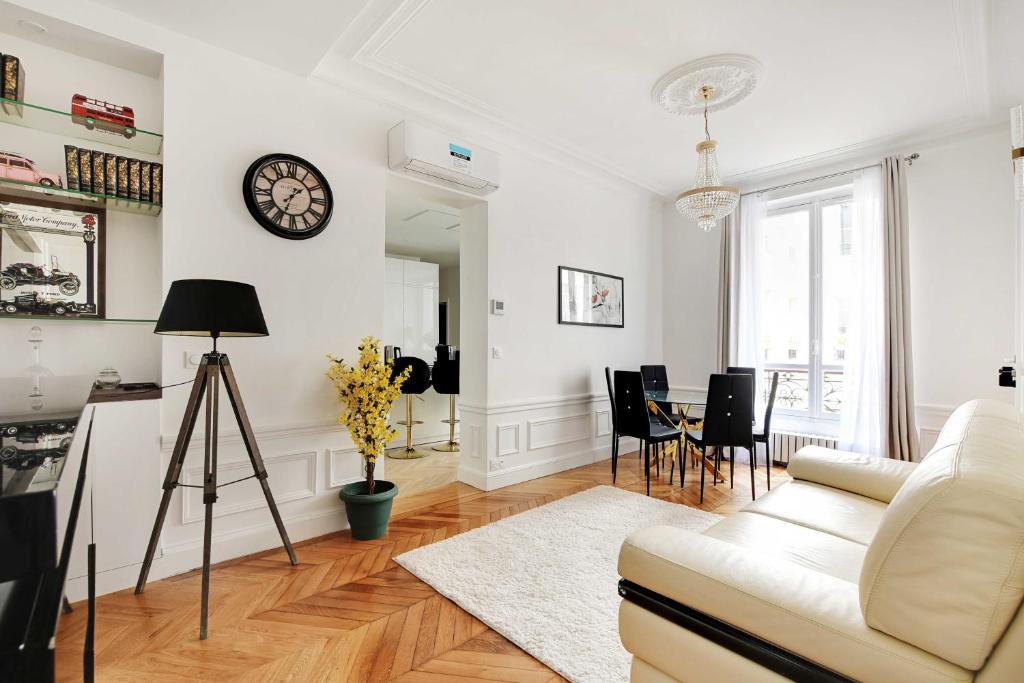 un salon avec un canapé et une horloge au mur dans l'établissement Dazzling flat - 3BD8P - Arc de Triomphe, à Paris