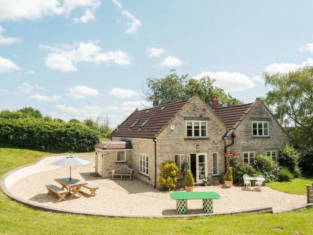a large stone house with a picnic table and an umbrella at Vine Cottage in Shepton Mallet