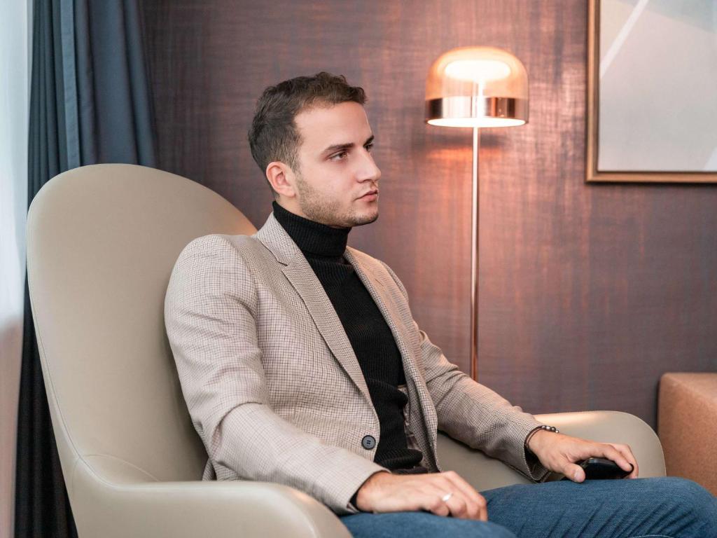 a man in a suit sitting in a chair at Sofitel Luxembourg Europe in Luxembourg