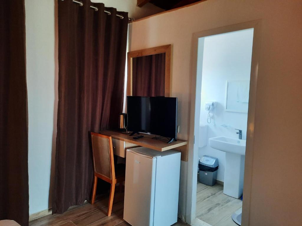 a room with a desk with a television and a bathroom at Apartments Alavana in Velipojë