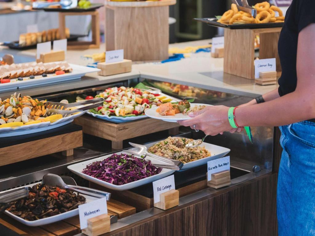 a woman holding a plate of food in a buffet at DoubleTree by Hilton Malta in St Paul's Bay