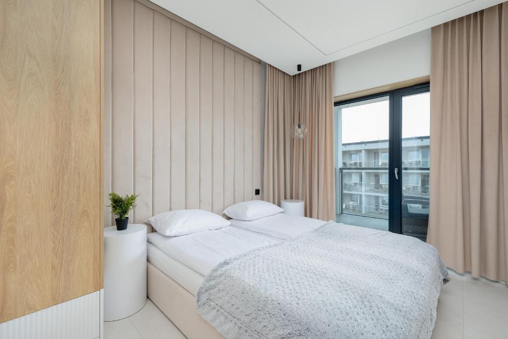 ein Schlafzimmer mit einem Bett und einem großen Fenster in der Unterkunft Nowoczesny Apartament Przy Plaży z Parkingiem by Noclegi Renters in Ustronie Morskie