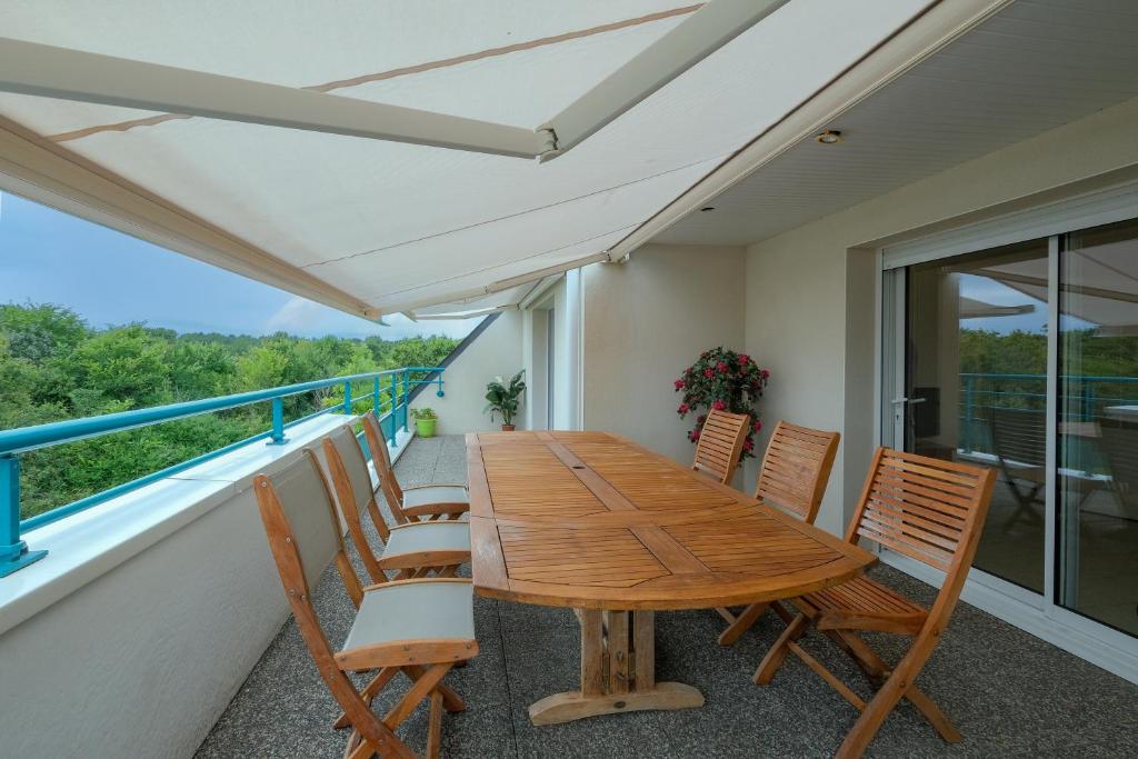 une table et des chaises en bois sur un balcon dans l'établissement Horizon d'Azur - Appt avec vue sur la fôret, à Saint-Nazaire