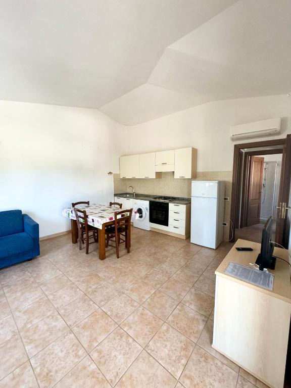 a kitchen with a table and a blue couch at Case vacanza Corallo - San Teodoro centro in San Teodoro
