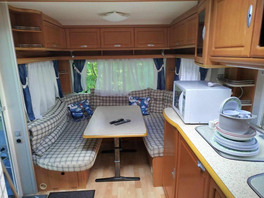 a kitchen with a table and a couch in an rv at Przyczepa campingowa in Grzybowo