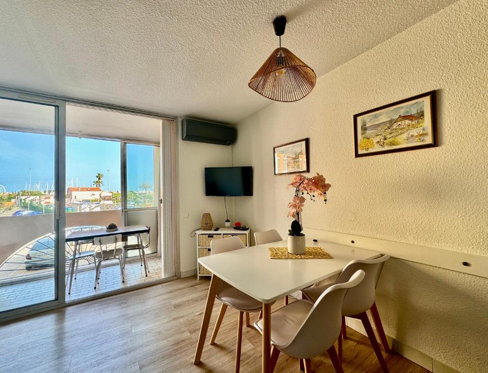 une salle à manger avec une table et des chaises et un balcon dans l'établissement Appartement Cap d'Agde, au Cap d'Agde