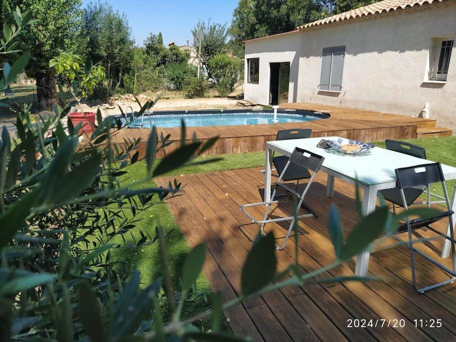 un patio avec une table et des chaises à côté d'une piscine dans l'établissement Maison nature, à Le Val