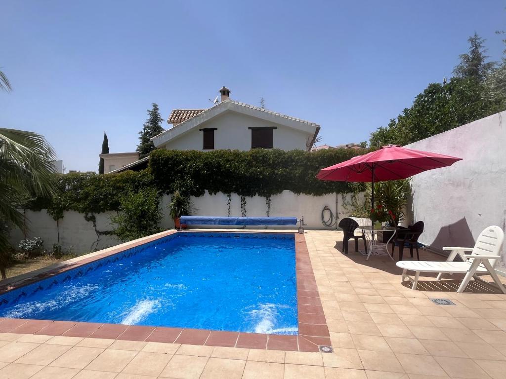 a swimming pool with a red umbrella and a house at LOFT Huetor Santillan in Huétor Santillán