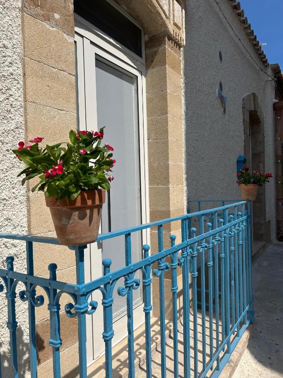 Una barandilla azul con una planta en maceta en una ventana. en Dimora Claramare, en Marzamemi