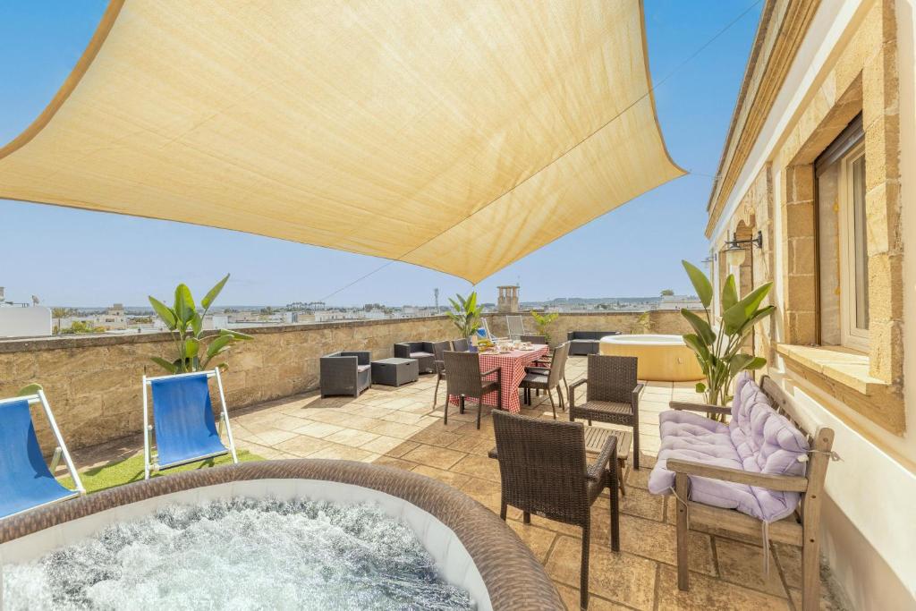 a hot tub on a patio with chairs and a table at Palazzo Lily in Racale