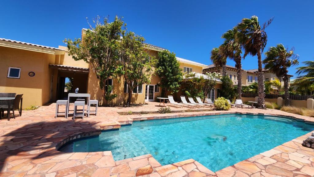 a swimming pool in front of a house at Villa Bella Mare Aruba - Steps to the beach in Palm-Eagle Beach