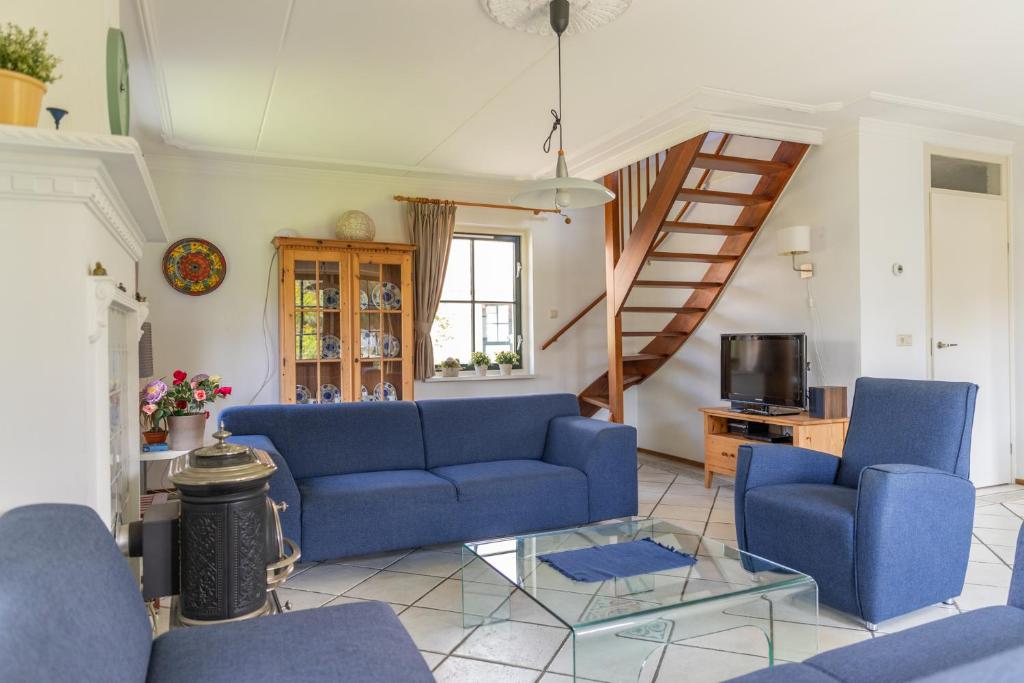 a living room with blue couches and a staircase at Buitenplaats 86 in Callantsoog
