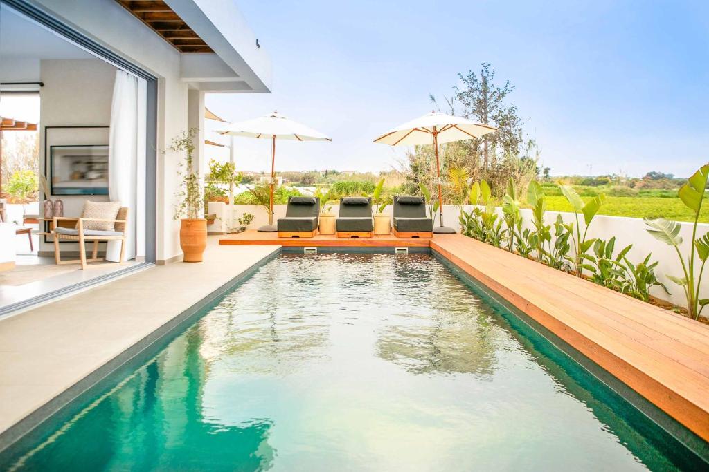 ein Infinity-Pool in einem Haus mit Stühlen und Sonnenschirmen in der Unterkunft Lora Pearl Luxury Villa in Protaras