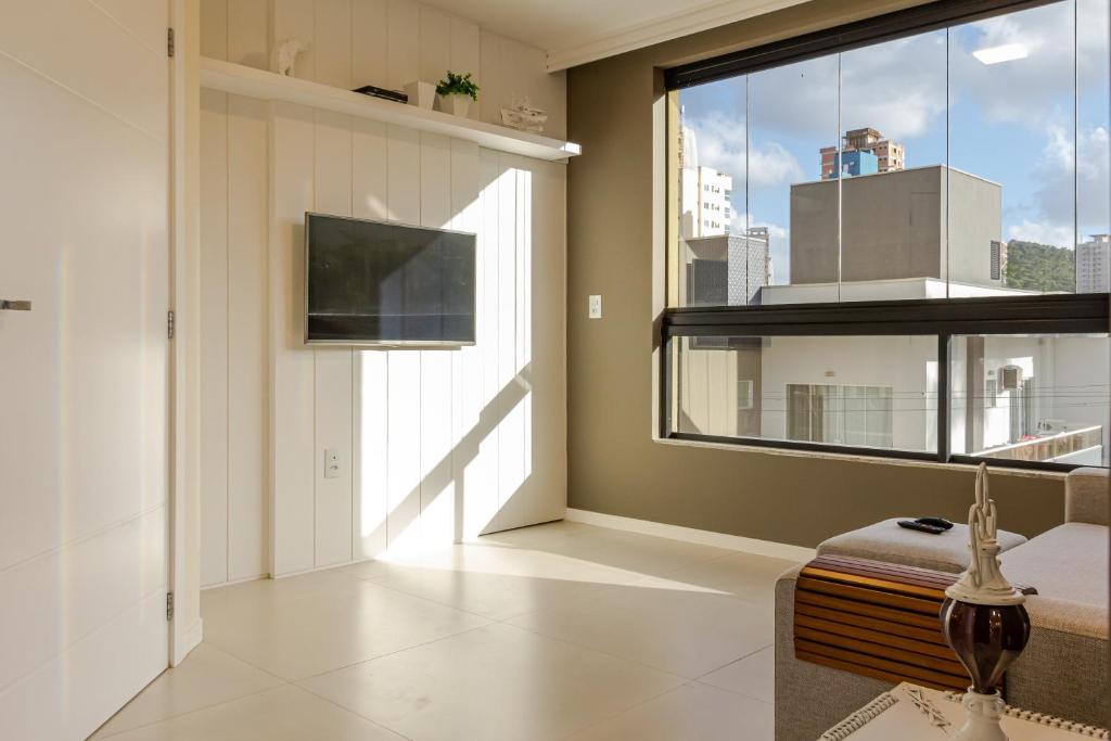 un salon avec une grande fenêtre et une télévision dans l'établissement Ap c/ Terraço, 2 quadras da Praia em Itapema P1771, à Itapema