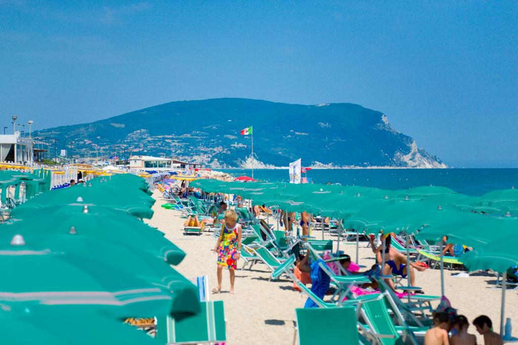 - un groupe de personnes sur une plage avec des chaises de plage vertes dans l'établissement Villaggio Turistico Internazionale, à Porto Recanati