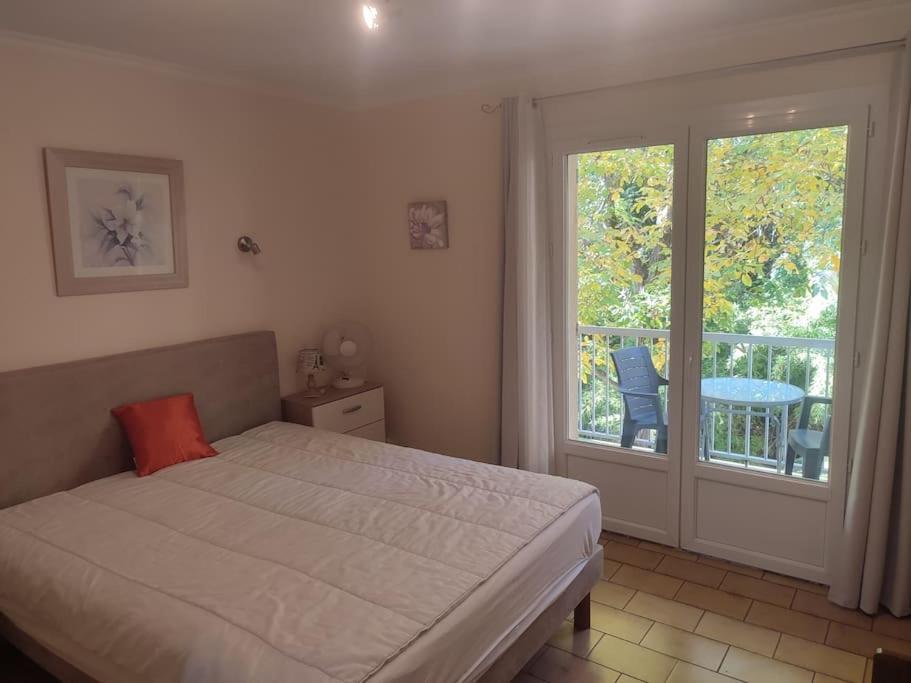 une chambre avec un lit et un balcon avec une table dans l'établissement T 1 avec terrasse face rivière à 1 min des thermes, à Gréoux-les-Bains