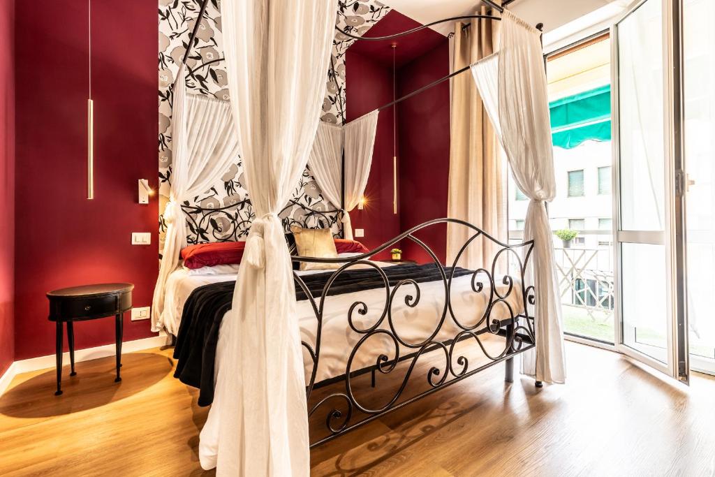 a bedroom with a canopy bed with red walls at ALE HOUSE in Arezzo