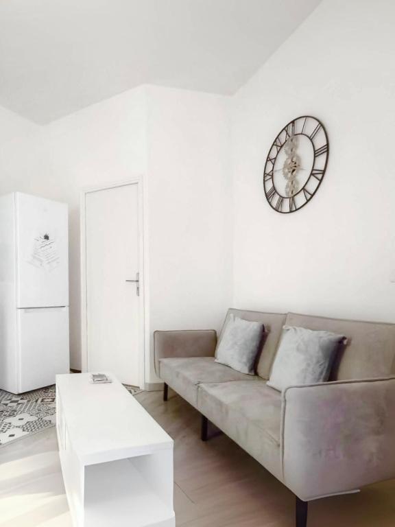 un salon avec un canapé et une horloge au mur dans l'établissement Bel appartement au Marais de Paris, à Paris