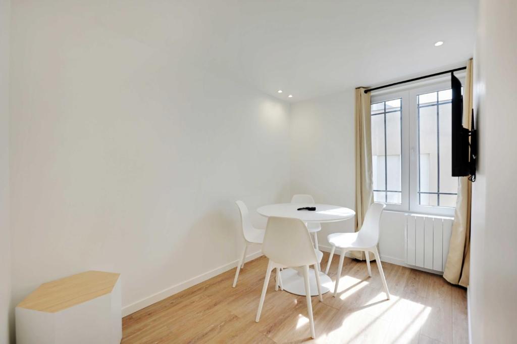 une table blanche et des chaises dans une pièce avec une fenêtre dans l'établissement Cosy, fully-equipped apt - 1BD-2P - near Paris, à Aubervilliers
