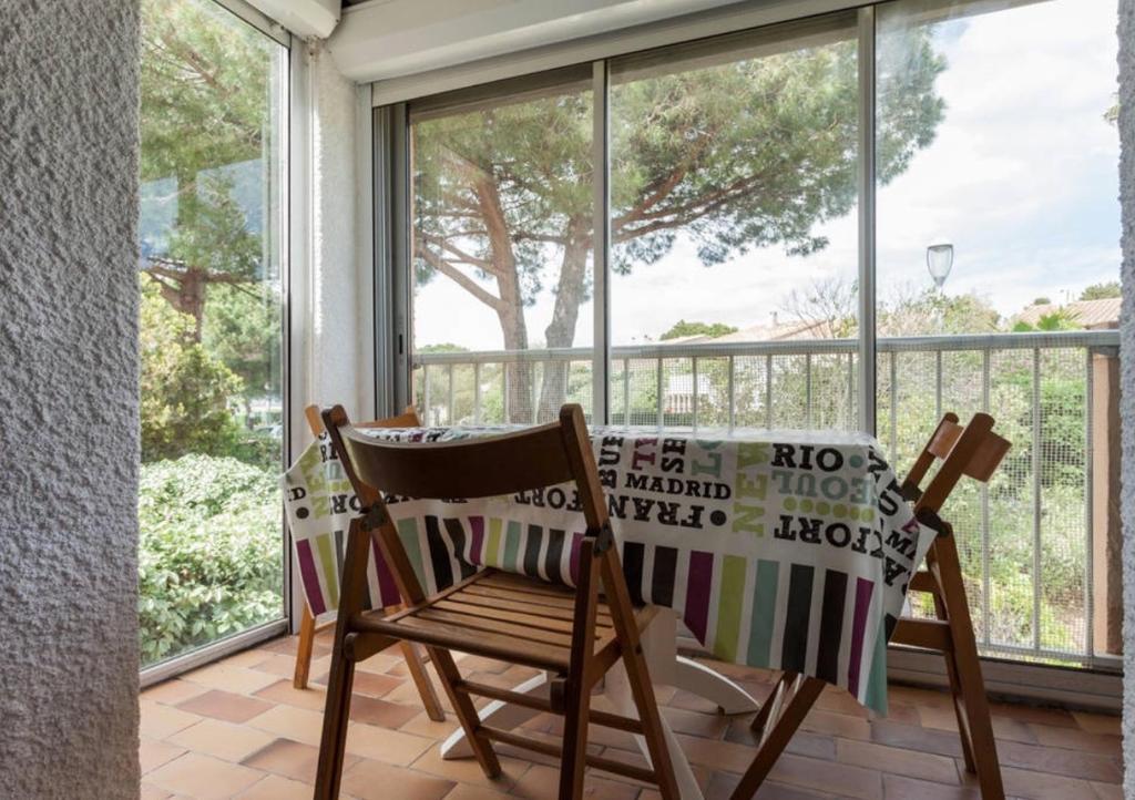 un fauteuil à bascule sur une terrasse couverte avec une fenêtre dans l'établissement Bel appartement avec balcon, au Cap d'Agde