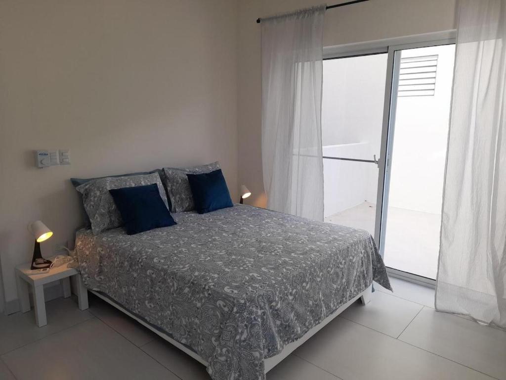 una camera da letto con un letto con cuscini blu e una finestra di villa paradise caribbean piscina privata 8 letti a Sosúa