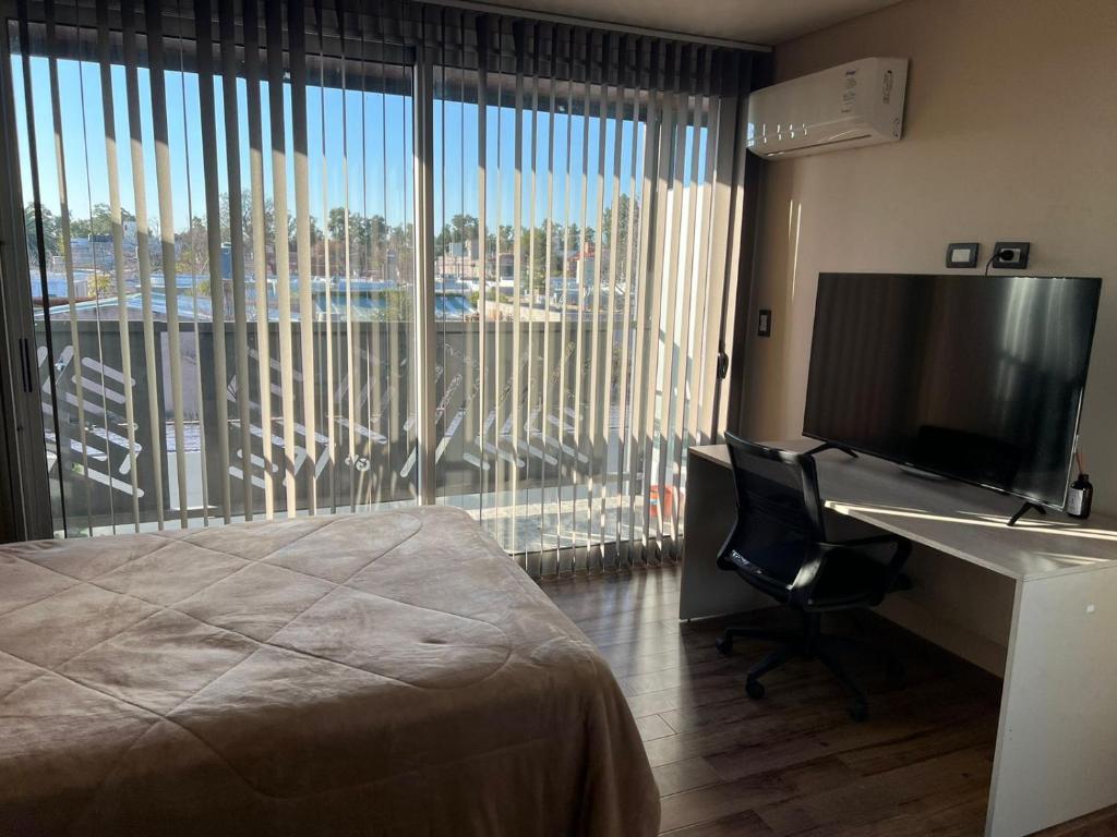 una camera d'albergo con un letto, una scrivania e una televisione di Garden Block Departamentos Temporarios a San Luis