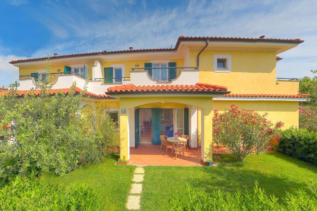 ein gelbes Haus mit einer Terrasse und einem Hof in der Unterkunft Residence I Giardini Del Conero in Porto Recanati
