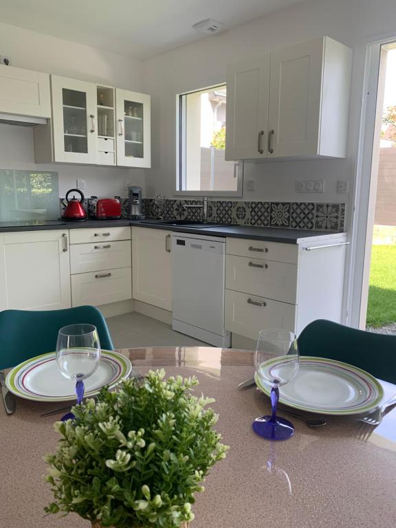 une cuisine avec une table avec des assiettes et des verres à vin dans l'établissement Maison 3 pièces - 2 chambres lits Queen Size avec wifi, à Grandchamp-des-Fontaines
