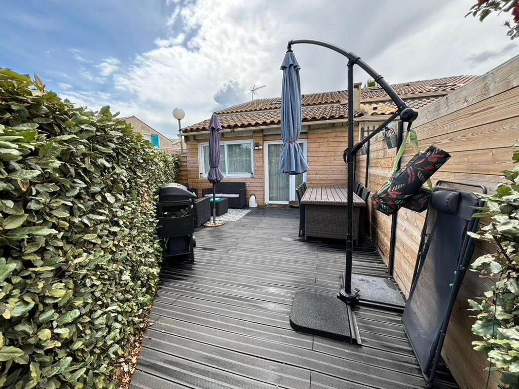 une terrasse en bois avec un parasol et un banc dans l'établissement La maison du bonheur, à Mèze