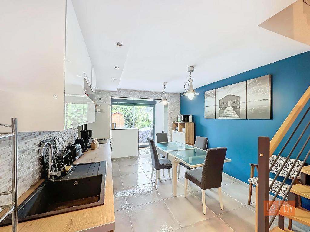 a dining room with a table and a blue wall at Le Petit Loft in Wimille