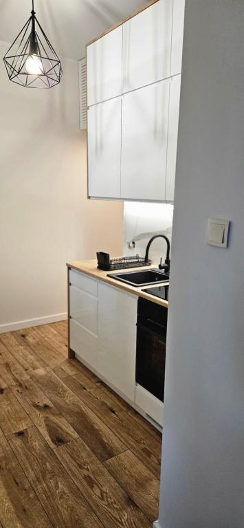 a kitchen with white cabinets and a wooden floor at Lipowy Kąt in Gołdap