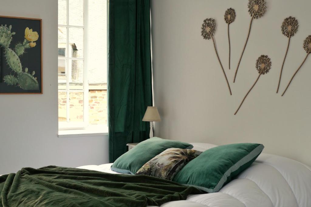 a bedroom with a bed with green pillows and a window at Les chambres de l'Elysée in Pontrieux