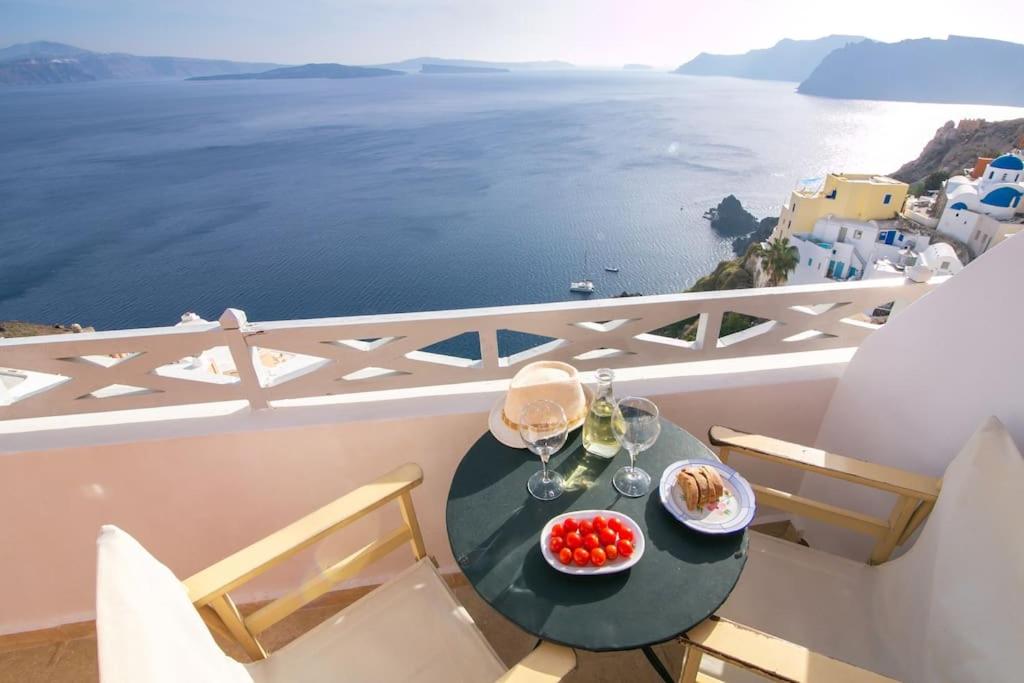 einen Tisch mit Speisen auf einem Balkon mit Meerblick in der Unterkunft Pano Meria Venetian Style Studio I in Oia