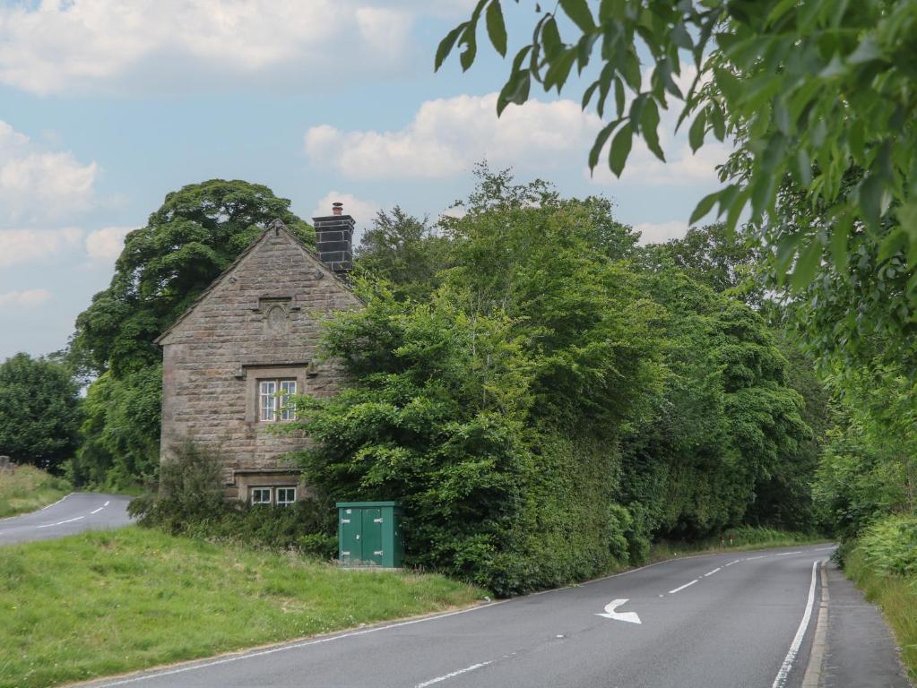 une vieille maison sur le côté d'une route dans l'établissement Whim Cottage, à Hathersage