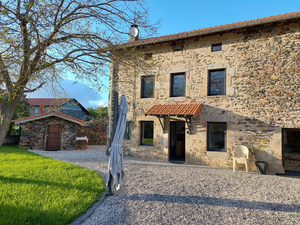 - un bâtiment en pierre avec un grand parapluie en face dans l'établissement L'échappée belle 43, à Retournac