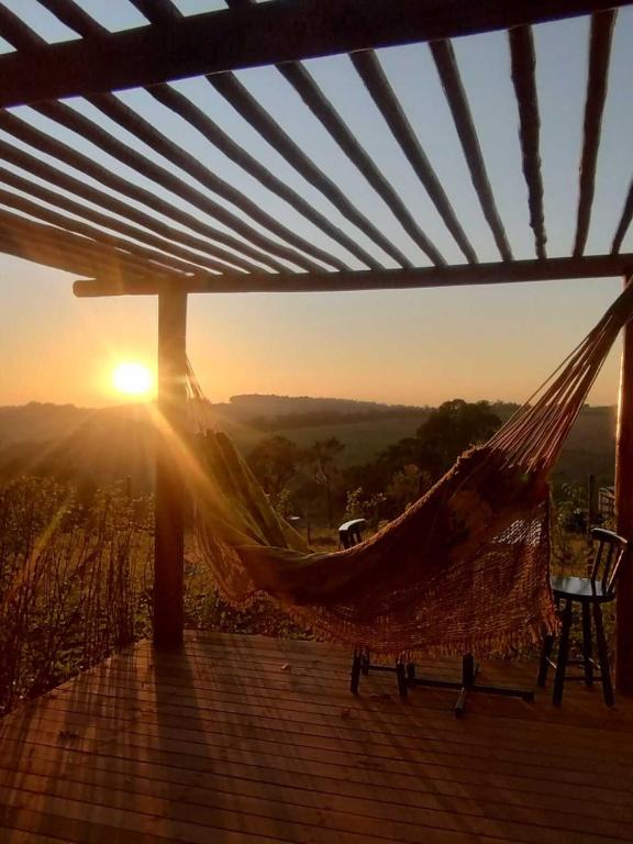 a hammock on a deck with the sunset in the background at Cabana com jacuzzi e churrasqueira - Ibiuna SP in Bairro Murundu