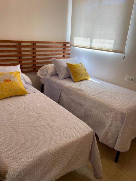a bedroom with two beds with yellow pillows on them at Magnífico piso con vistas al mar en Moncofa in Moncófar