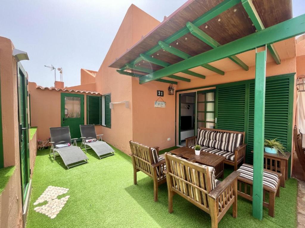 a patio with chairs and a table on the grass at Ten-Beau Relax Bungalow in Maspalomas