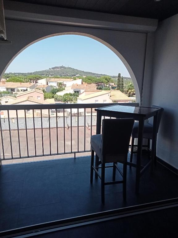une table et des chaises dans une pièce avec une grande fenêtre dans l'établissement Studio Port Soleil Naturiste Cap D'Agde, au Cap d'Agde