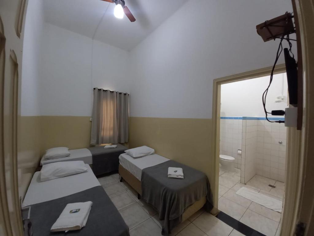 a hospital room with three beds and a shower at Hotel Central in Araçatuba